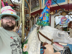 The carousel is decorated for the occasion with party hats and fun birthday signs.